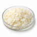 Illustration of pale ivory Cocamide MIPA flakes in a clear glass dish