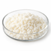 Off-white Montanov 202 emulsifier pellets in a clear glass Petri dish on white